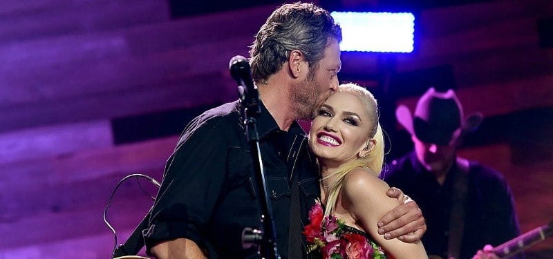 Gwen Stefani rocking her signature red lipstick as Black Shelton hugs her.