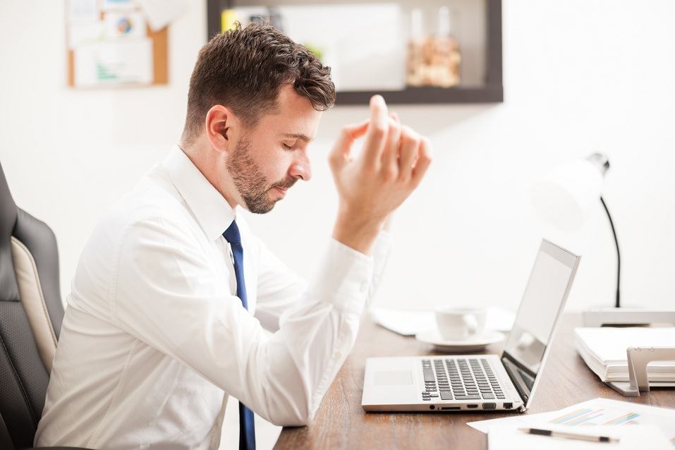 A young man does some meditation exercises in front of his laptop