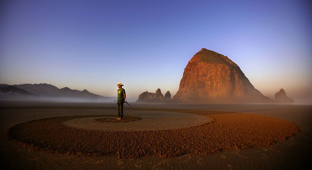 An artist stands on the sand in Cannon Beach, Oregon