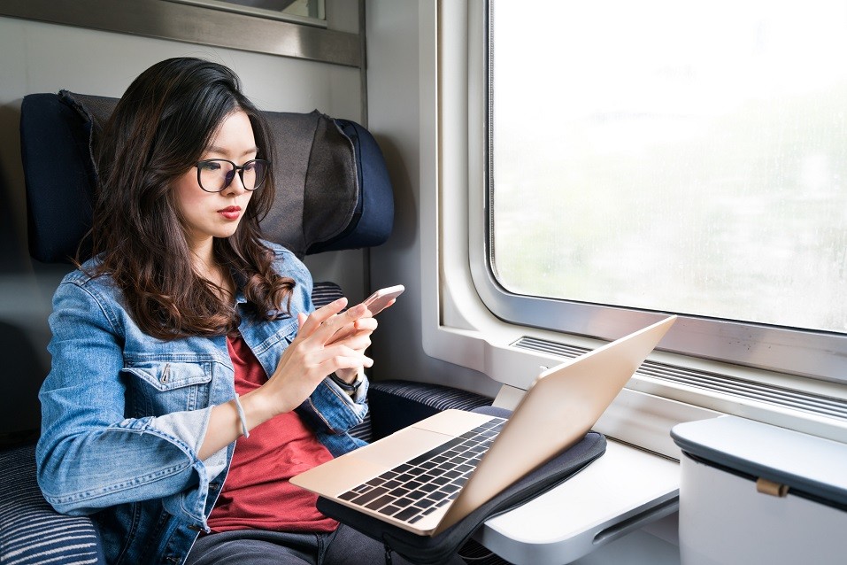 woman using smartphone and laptop on train