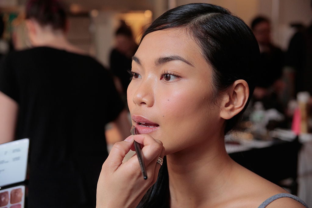Backstage a model gets makeup applied before the David's Bridal Spring/Summer 2017