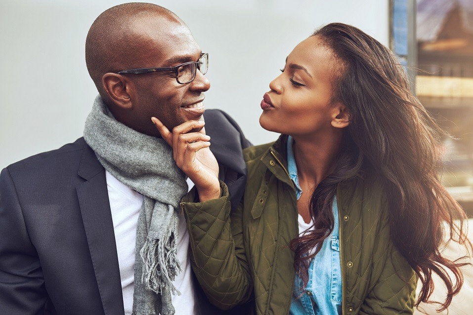 A young African American woman purses her lips as she awaits a kiss from her partner