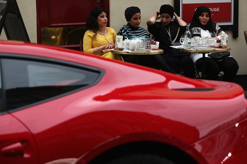 Wealthy diners eat in front of a Ferrari.