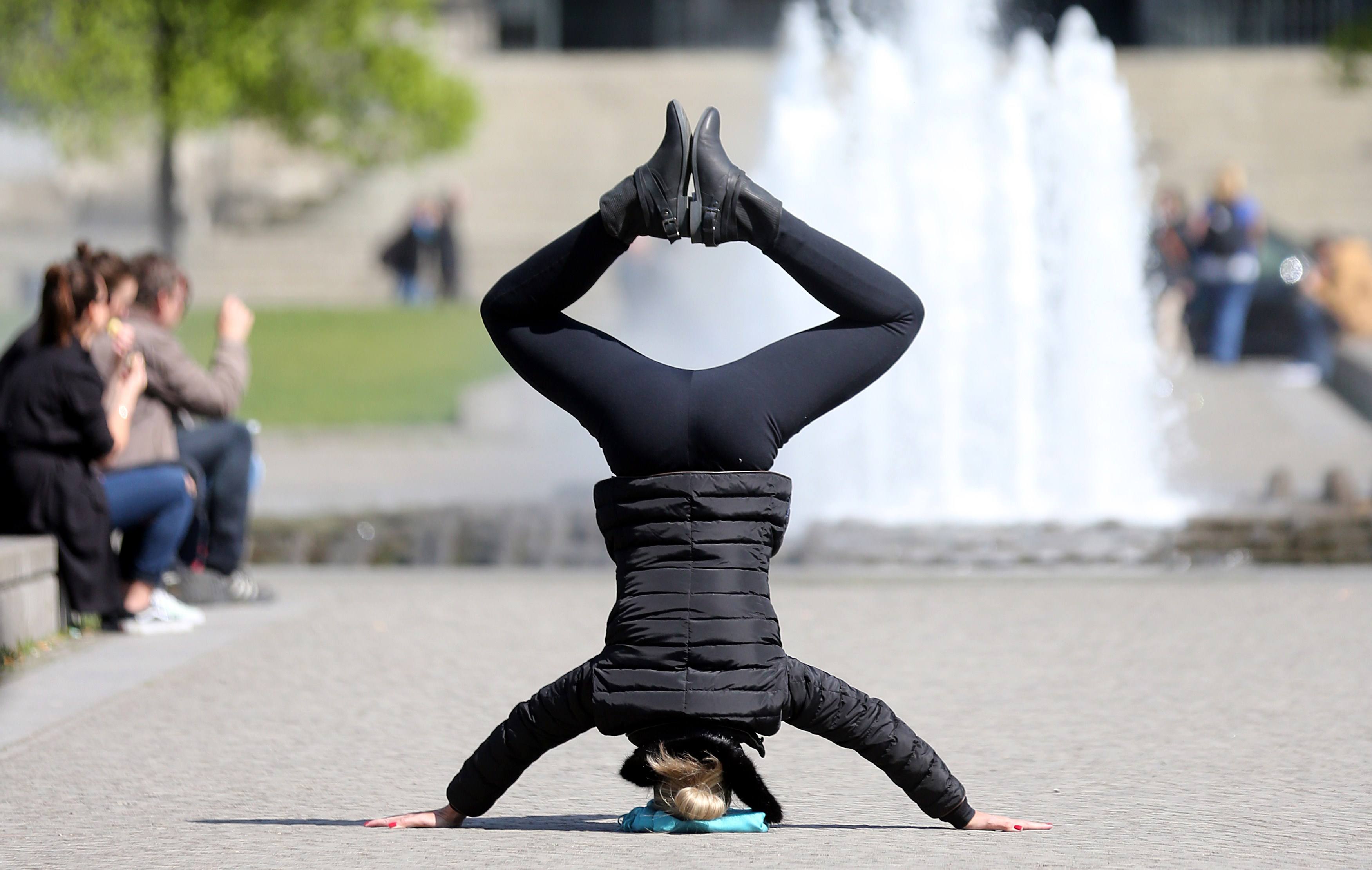 A woman makes a headstand in a park