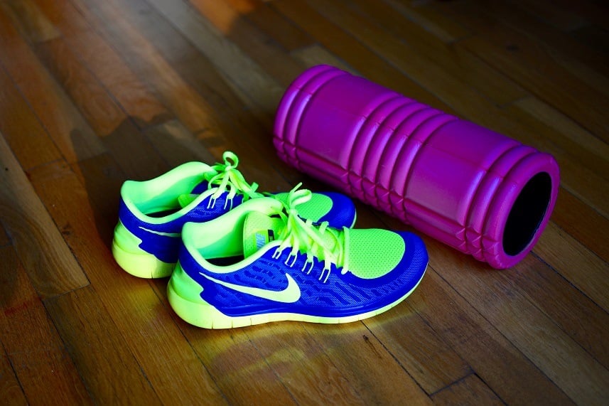 Men's Nike running shoes in green and blue and a violet foam roller