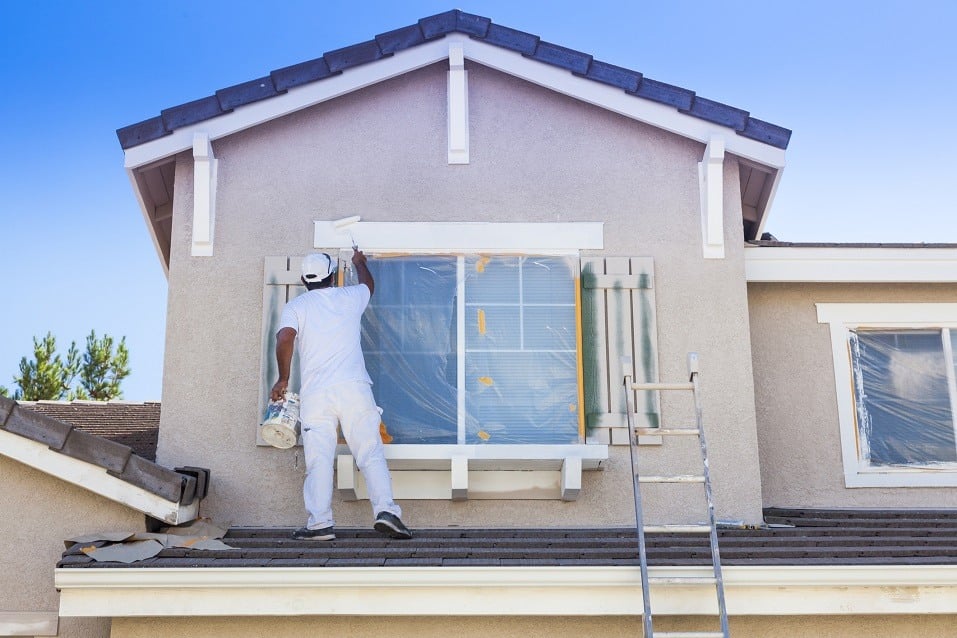 Person paints trim of house white