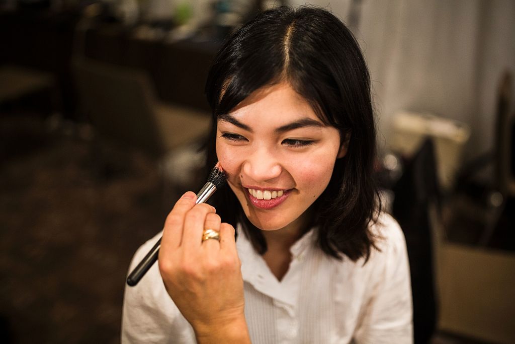 a stylist works on the makeup for Japanese model Rina Fukushi