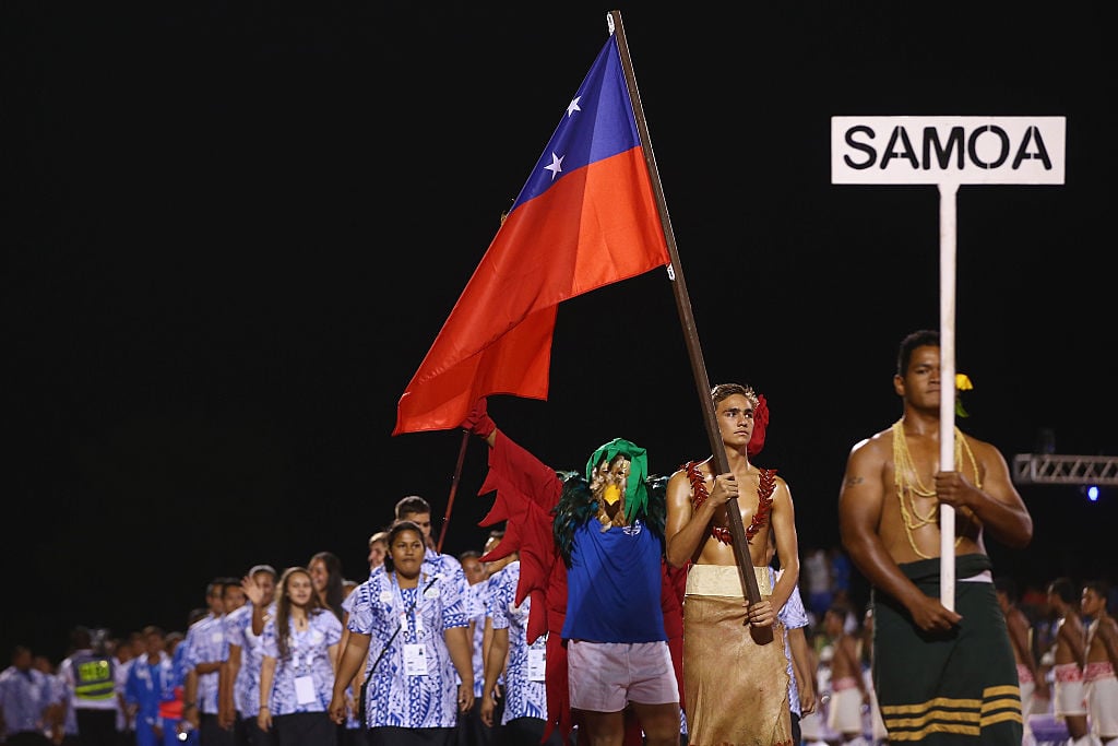 Brandon Schuster of Samoa carries his country flag as he lead the Samoa team