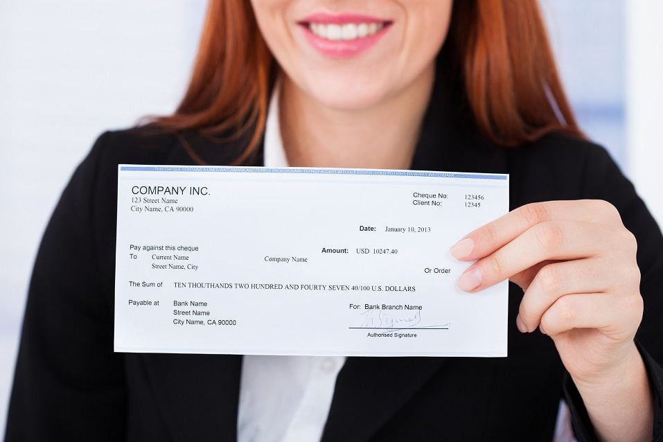 Smiling businesswoman holding check