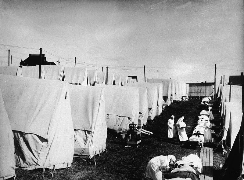 Nurses care for victims of a Spanish influenza epidemic outdoors amidst canvas tents