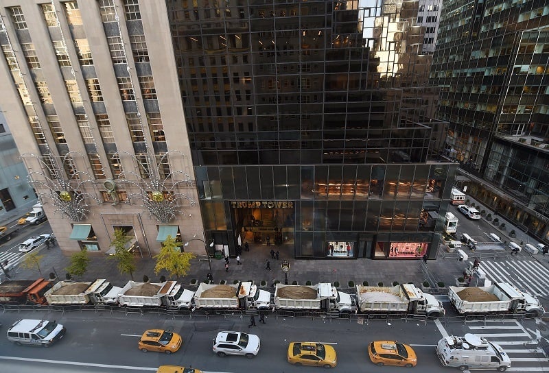 A protective barrier of Sanitation Department trucks parked in front of Trump Tower
