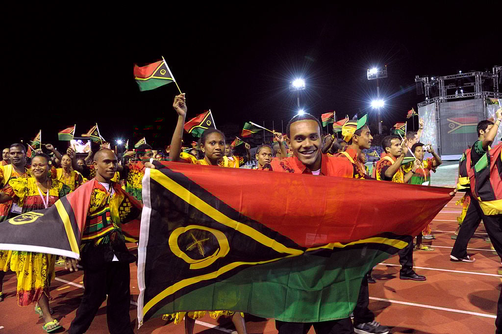 The Vanuatu delegation wave flags as they attend the Olympics