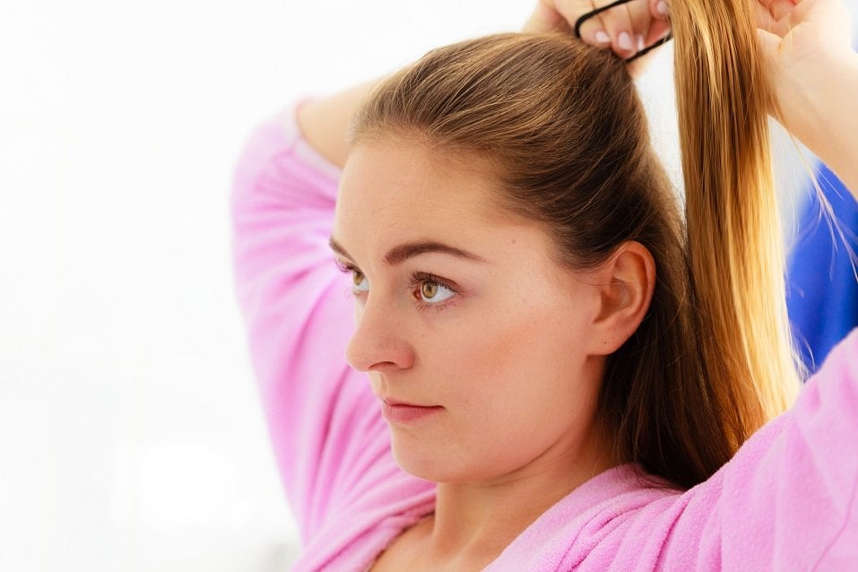 Woman combing brushing her long smooth hair in bathroom
