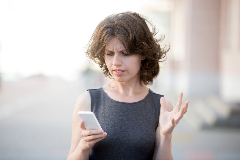 young woman holding cellphone in hands on the street in summer