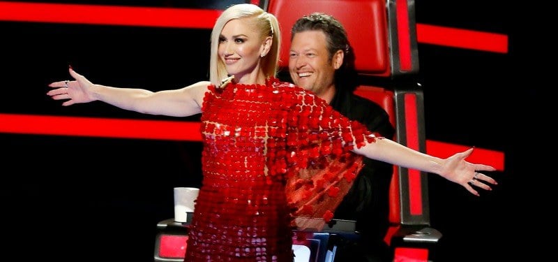 Gwen Stefani stands in front of Blake Shelton with her arms stretched out on The Voice.