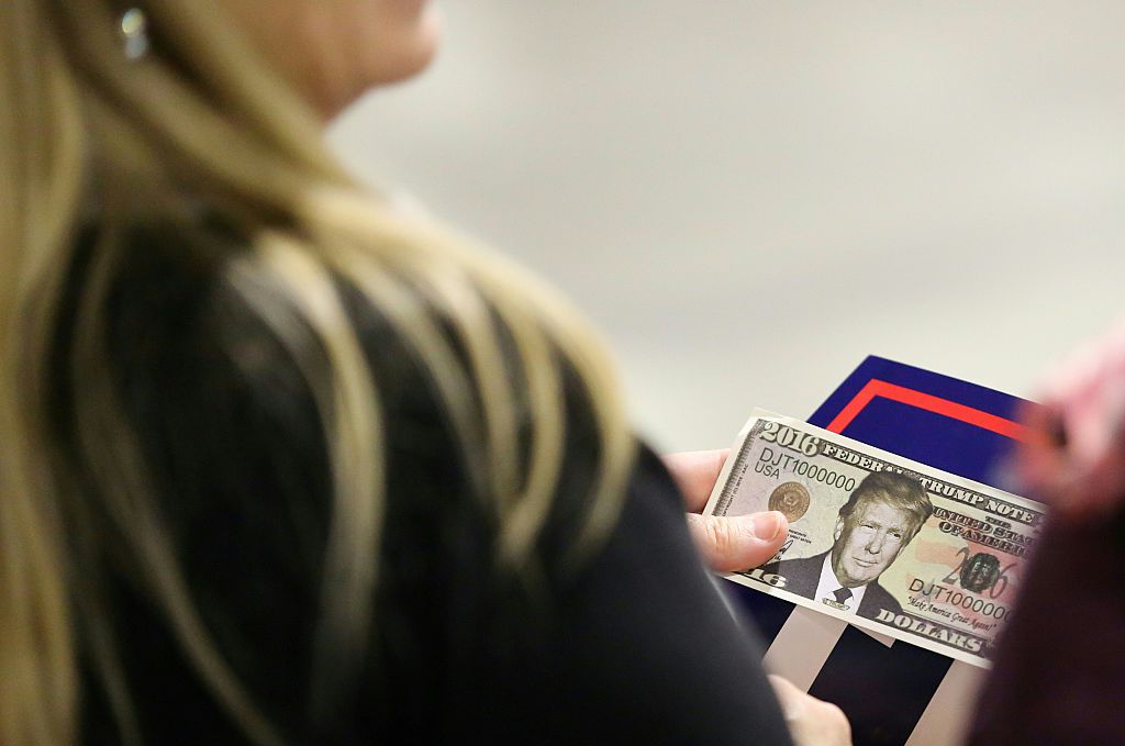 A woman holds fake money with Trump's face on it