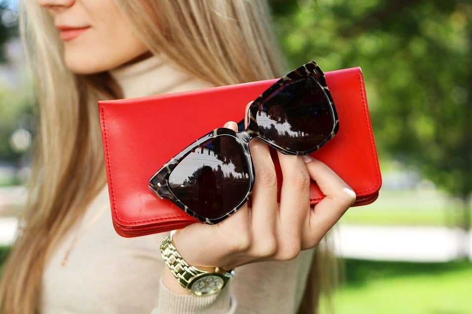 Woman hold red purse clutch in hand with black trendy sunglasses