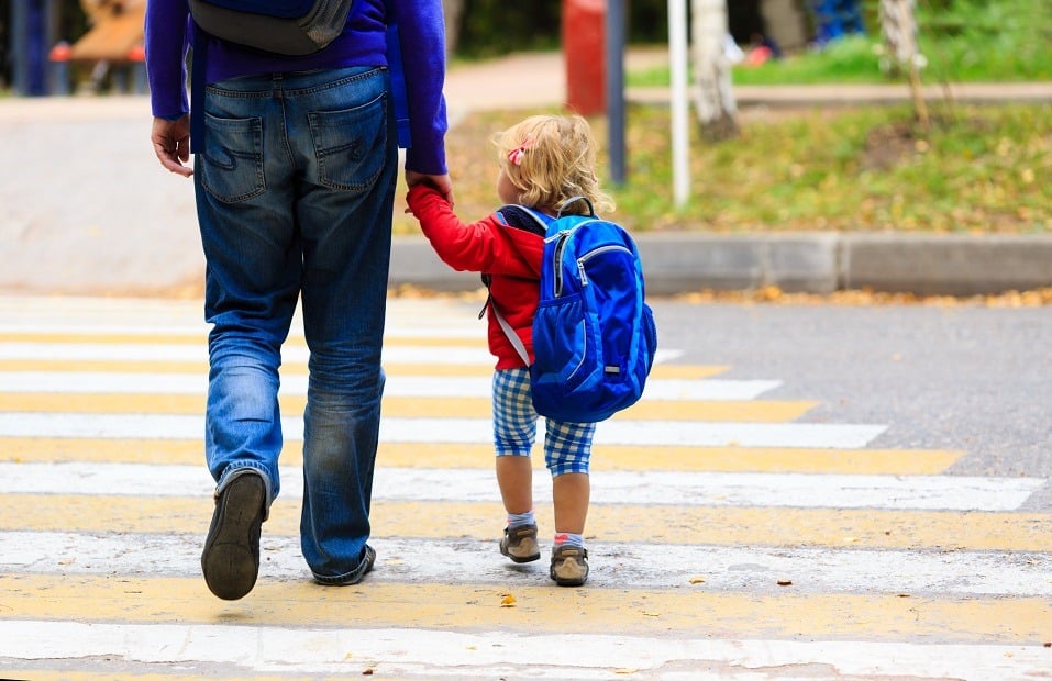 father walking little daughter with backpack