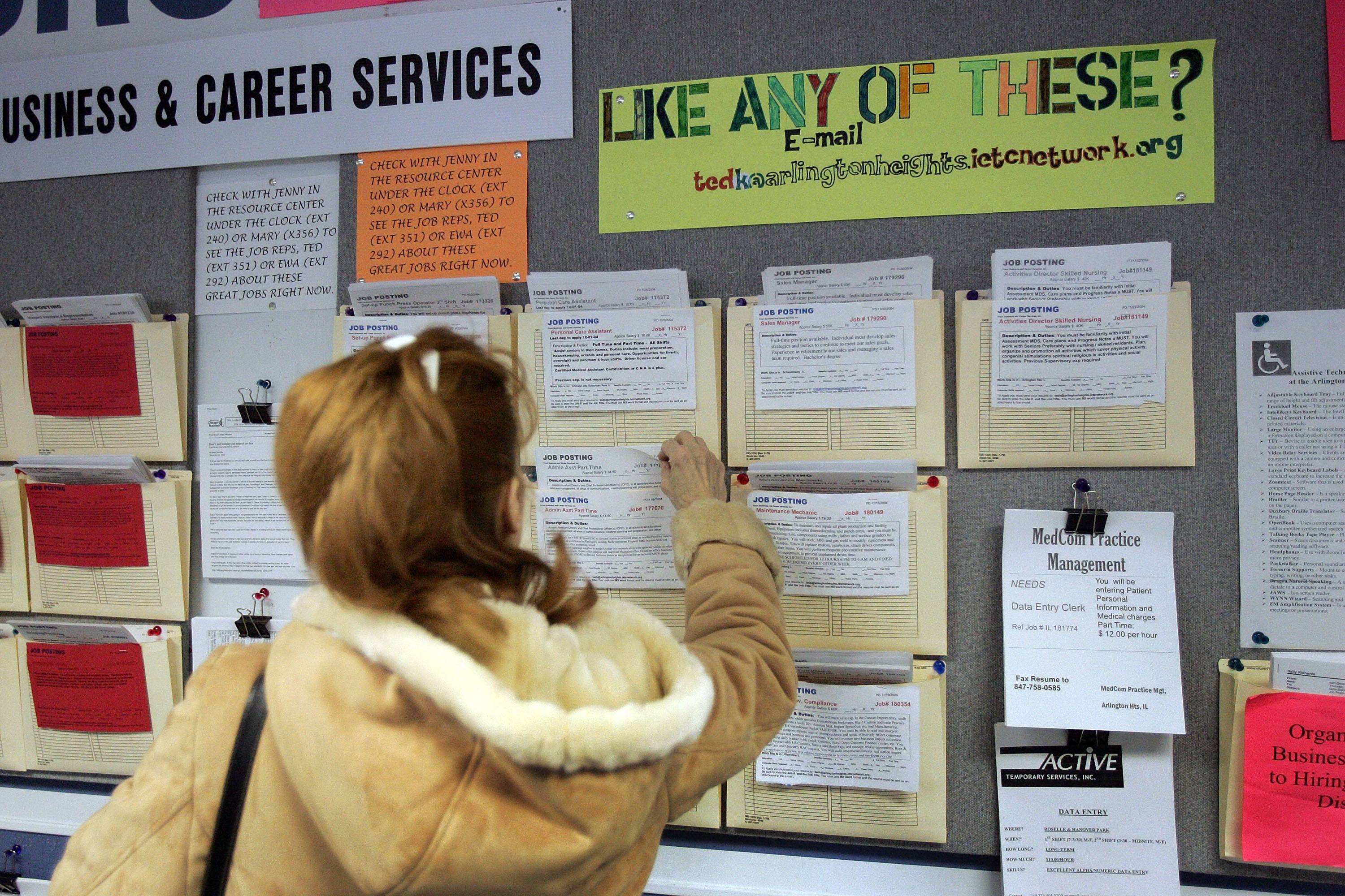 A woman looks at a board for a new job alert