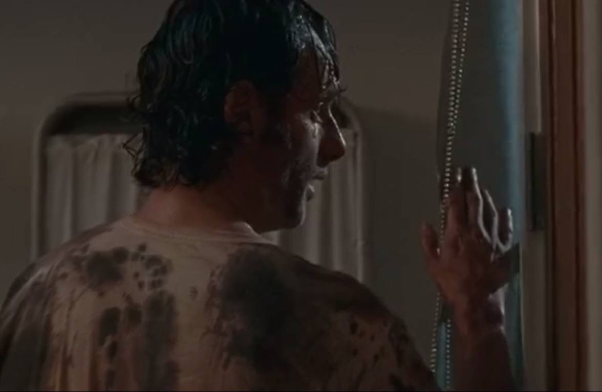 Rick stands in front of a window while wearing a blood-drenched shirt. Rick stands in front of a window while wearing a blood-drenched shirt.