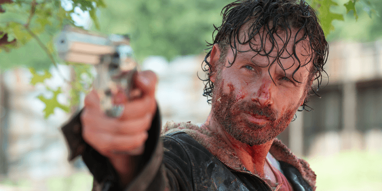 Rick Grimes points a gun while covered in blood. Rick Grimes points a gun while covered in blood.