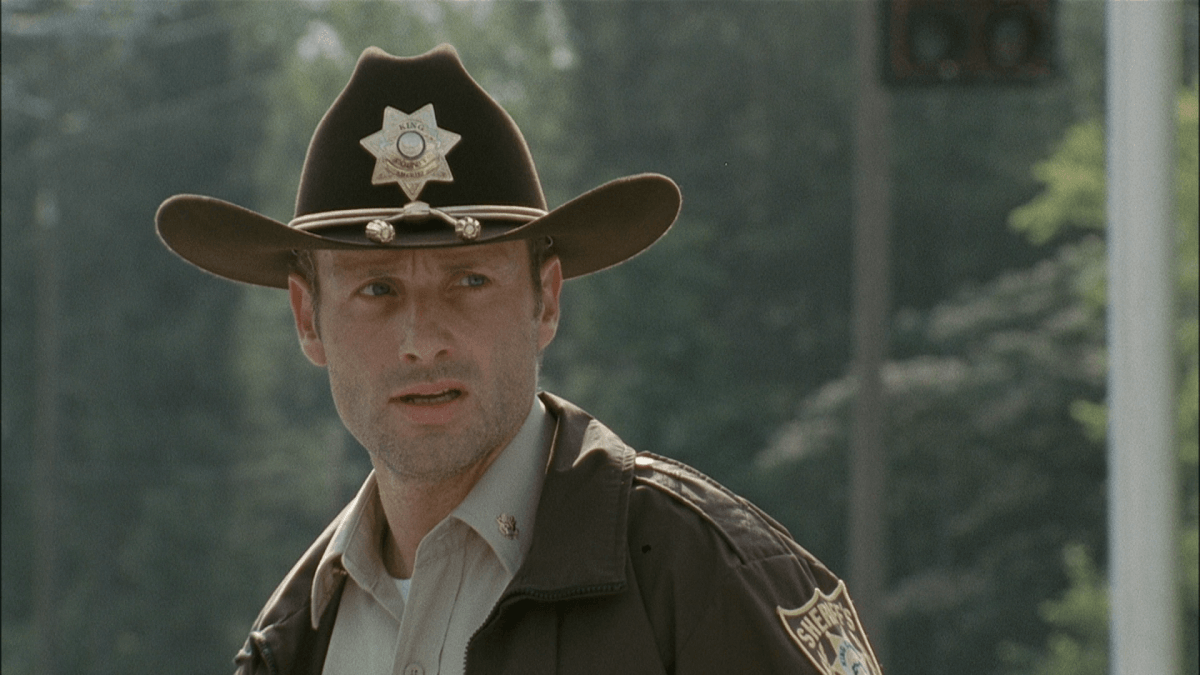 Rick Grimes, wearing a sheriff's outfit, and looking to his left.