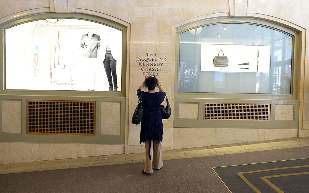 A woman takes a photo of a name plate of Jacqueline Kennedy.