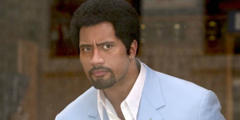 Dwayne Johnson is in a powder blue suit jacket and has an afro.