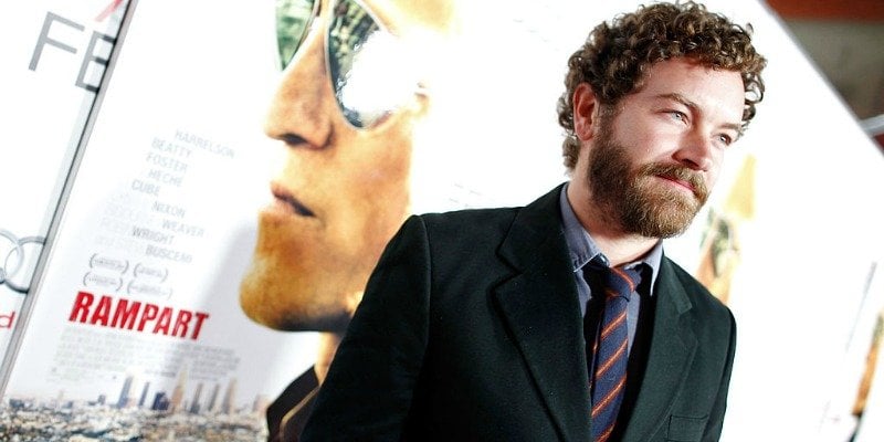 Danny Masterson stands in front of a Rampart poster