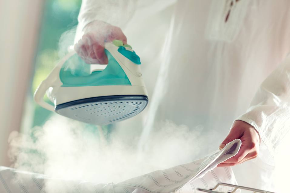 Woman's hands holding hot iron
