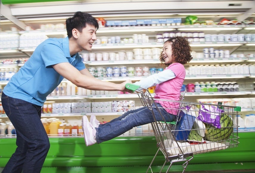 Father pushing daughter in shopping cart