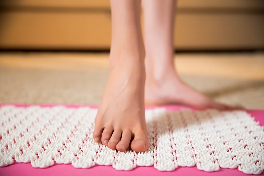 Female feet standing on acupressure mat