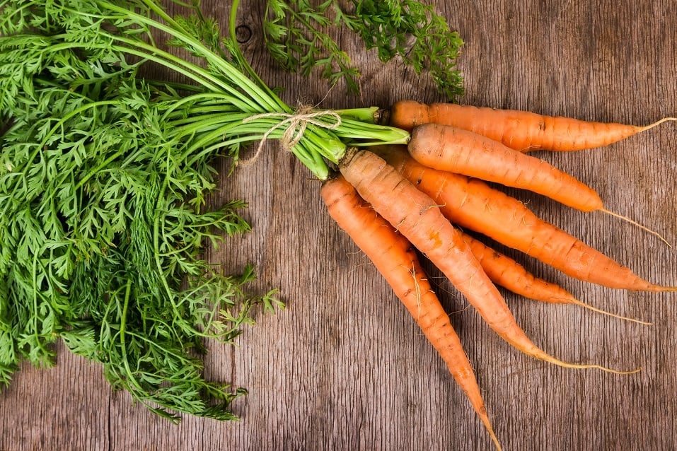 Fresh carrots arranged on a wooden background.
