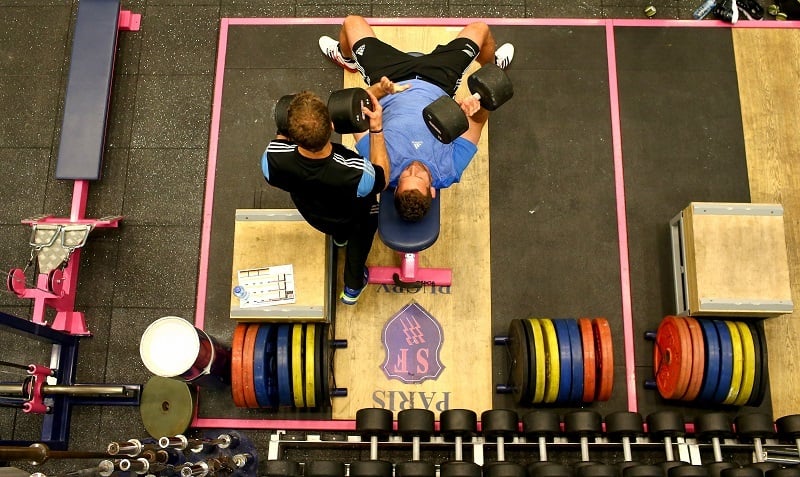 A man works out with a trainer in a gym