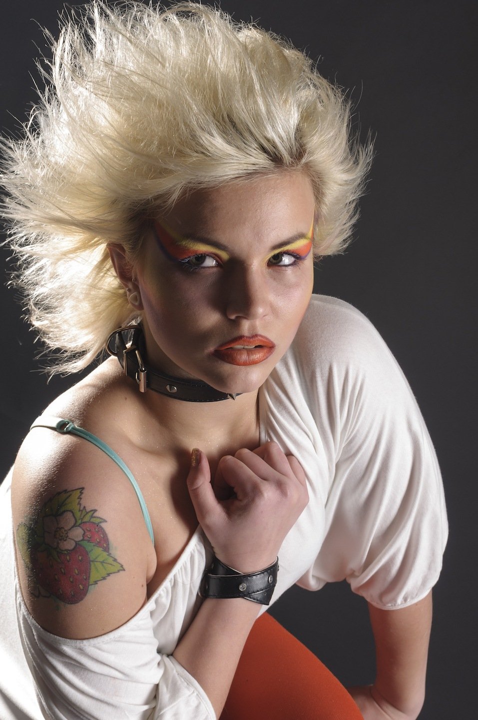 Young woman in punk look is wearing red tights and a white shirt in the 80s style.