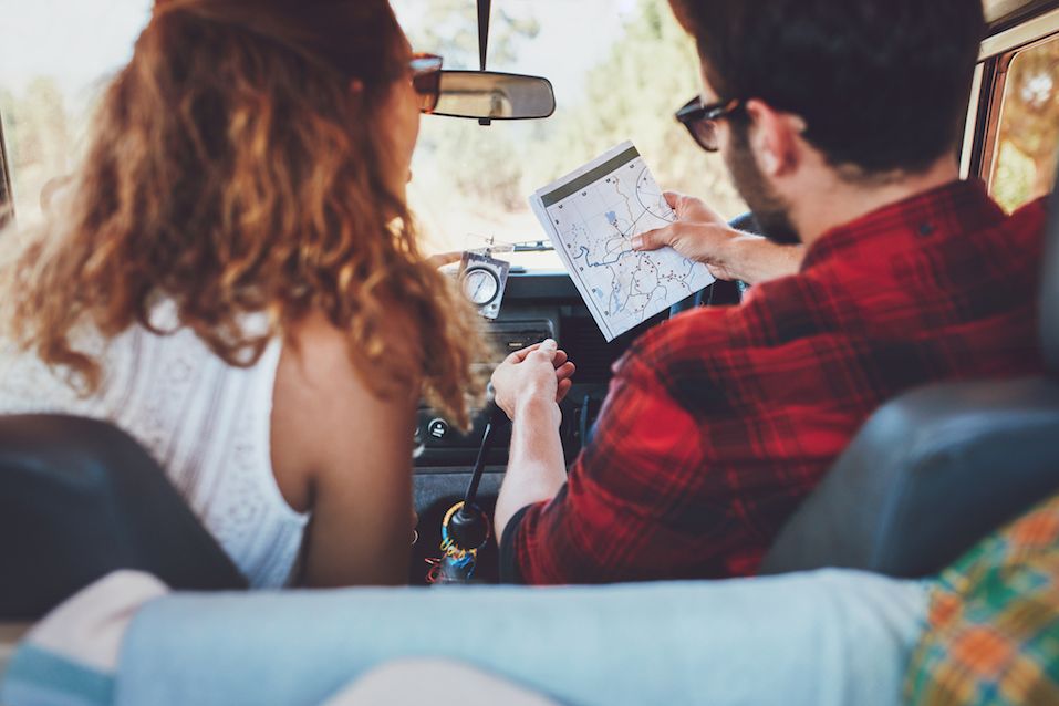 couple in a car on a road trip looking at a map
