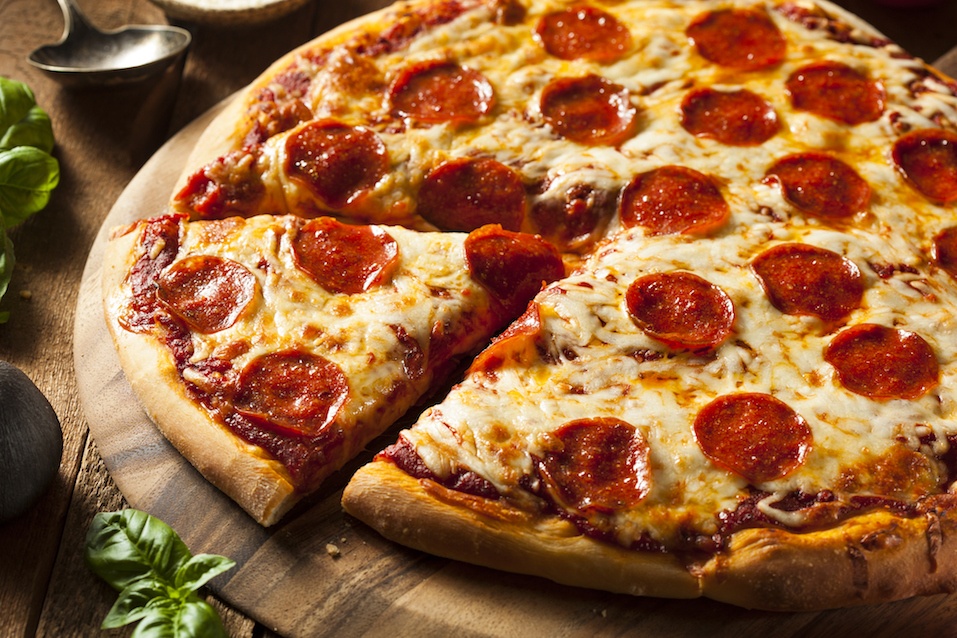 Cheesy pepperoni pizza with one section cut into a slice.