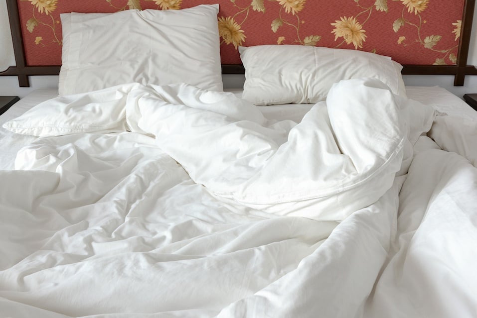 untidy bed with a white crumpled blanket