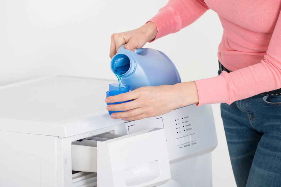 Female Hand Pouring Detergent In The Blue Bottle Cap