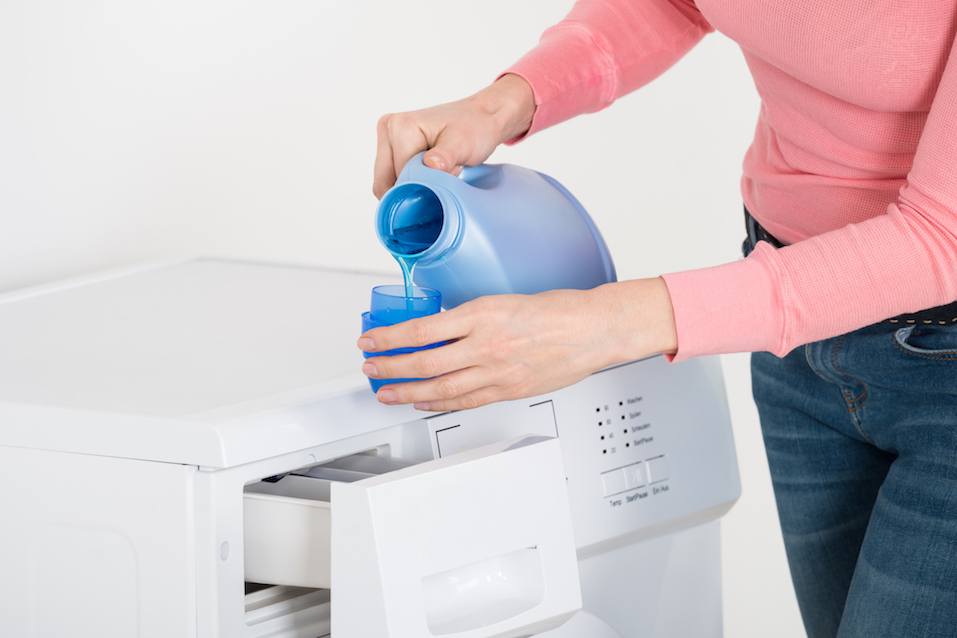 Female hand pouring detergent bottle in blue hat