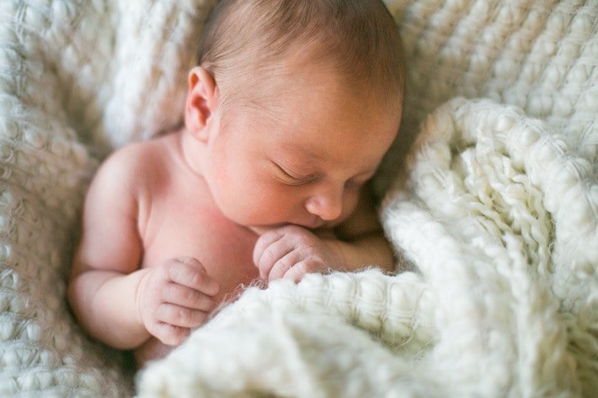 Baby boy sleeps wrapped in a white fuzzy blanket