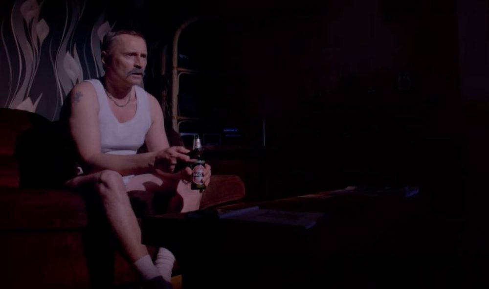 Robert Carlyle sitting with a beer in T2: Trainspotting