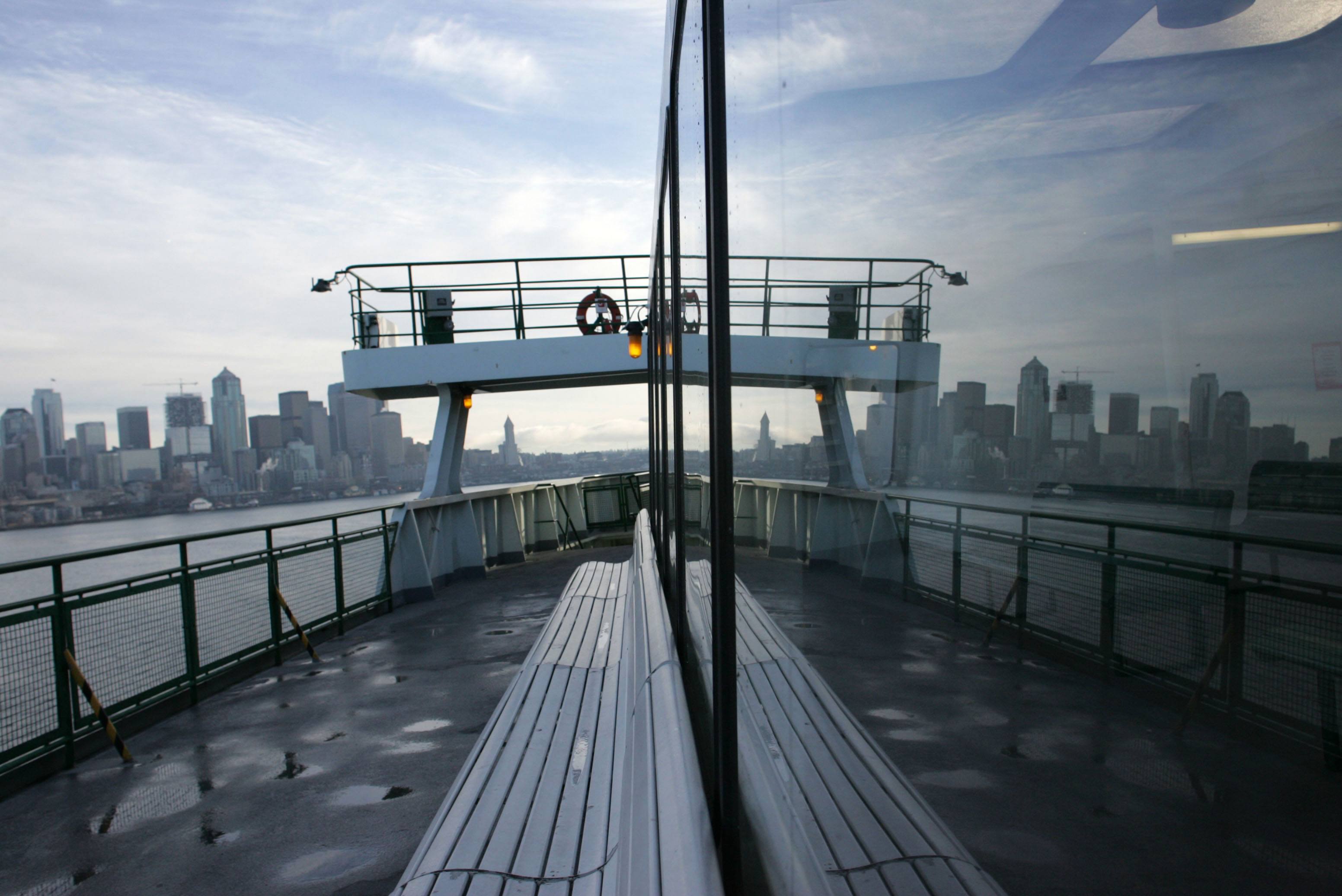 The Seattle skyline is reflected in the window of a Washington State Ferry