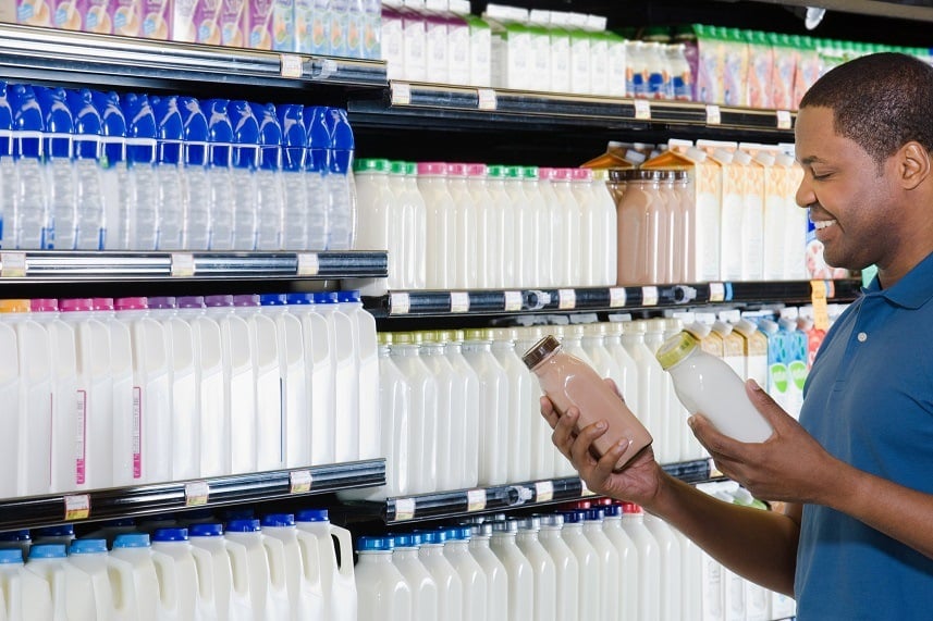 Young man in supermarket choosing milk