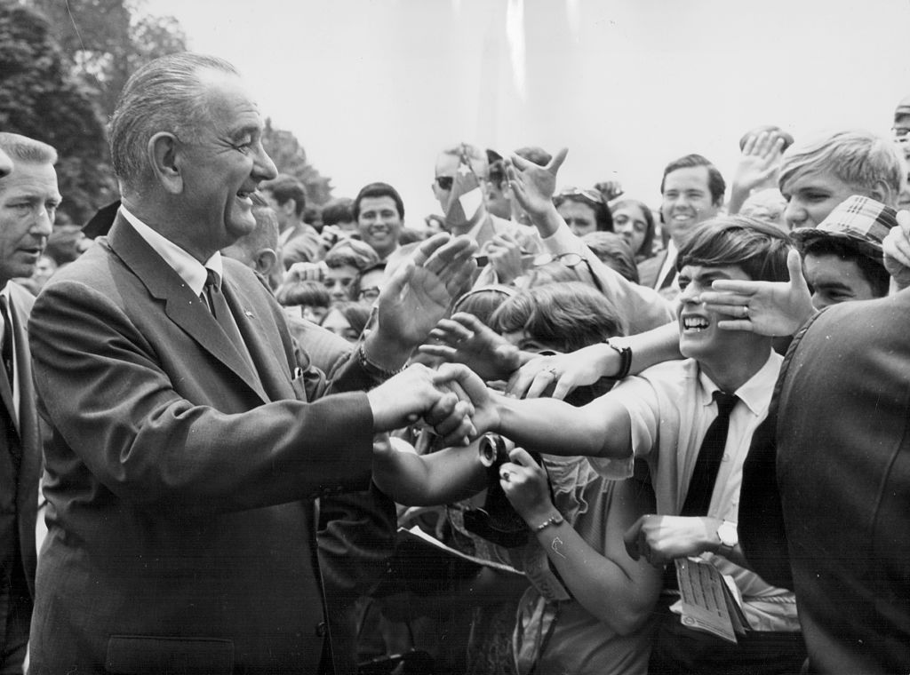 US President Lyndon B Johnson shaking the hands of crowds of people