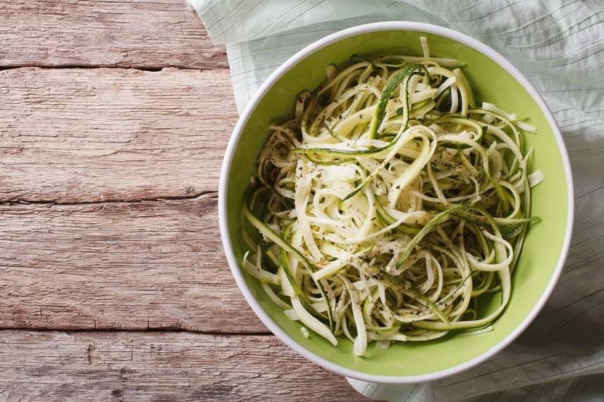 Raw zucchini pasta in a bowl close up on the table. horizontal top view.