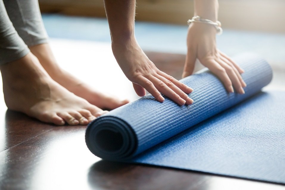 Young woman folding blue yoga mat