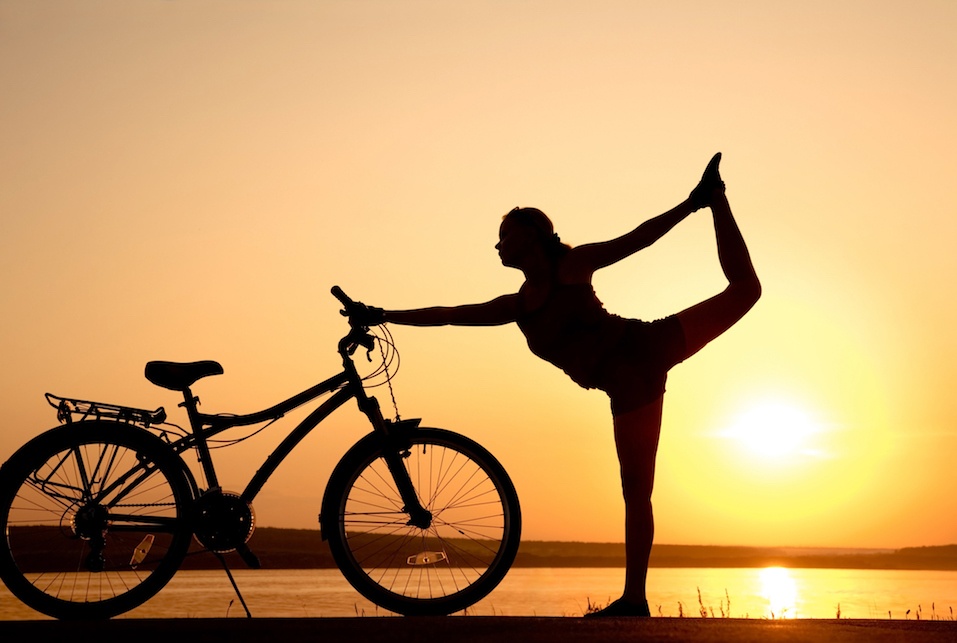 woman doing yoga next to her bike woman doing yoga next to her bike