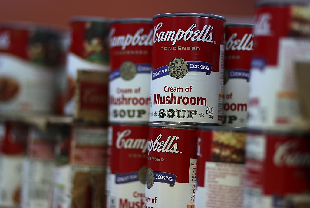 Cans of Campbell's soup are displayed on a supermarket shelf