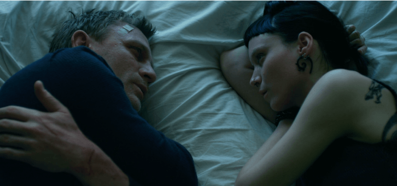 Mikael and Lisbeth lying in bed looking at each other in The Girl with the Dragon Tattoo